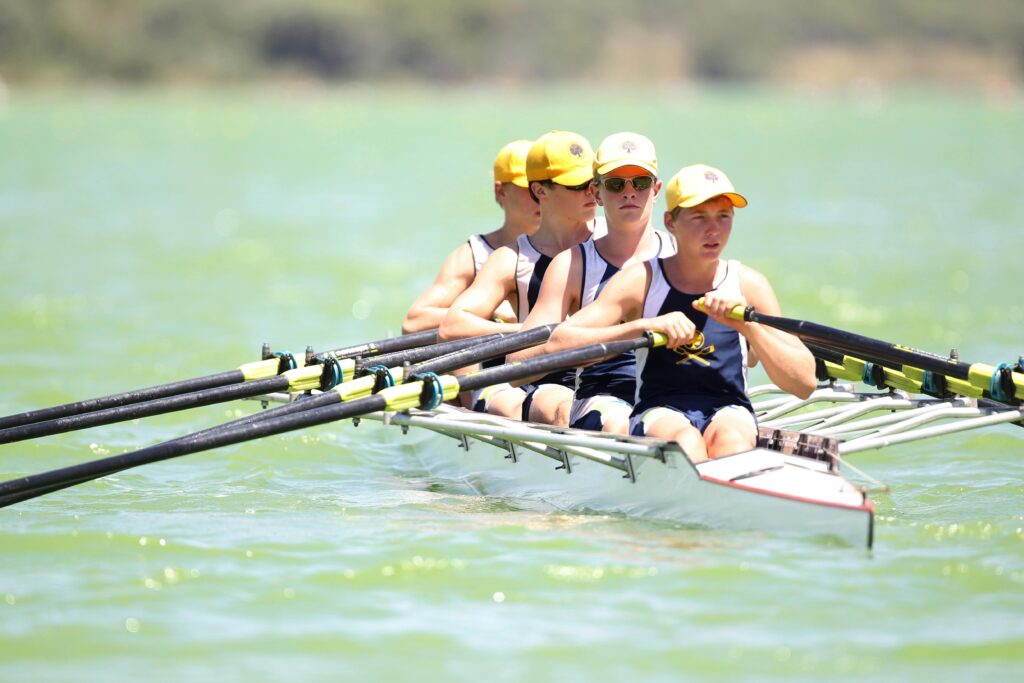 Close up shot of a team of 4 young rowers on an open body of water